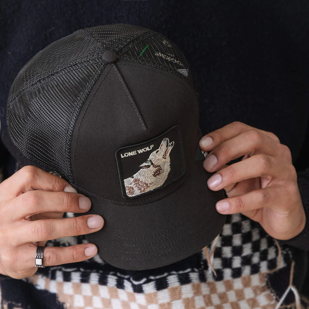 Goorin Bros lippis Lone Wolf Trucker, musta, jossa verkkopintainen taustaosa ja etupuolella harmaavalkoinen susiaiheinen brodeeraus, joustava takakiinnitys.
