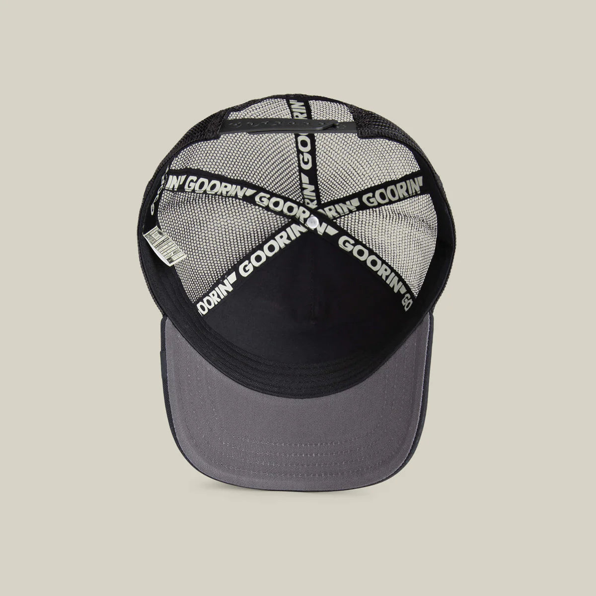 Goorin Bros lippis Lone Wolf Trucker, mustanvärinen verkkopäällysteinen takakallistettu malli, harmaa lippa, mustat ja valkoiset logonauhat sisäpuolella.