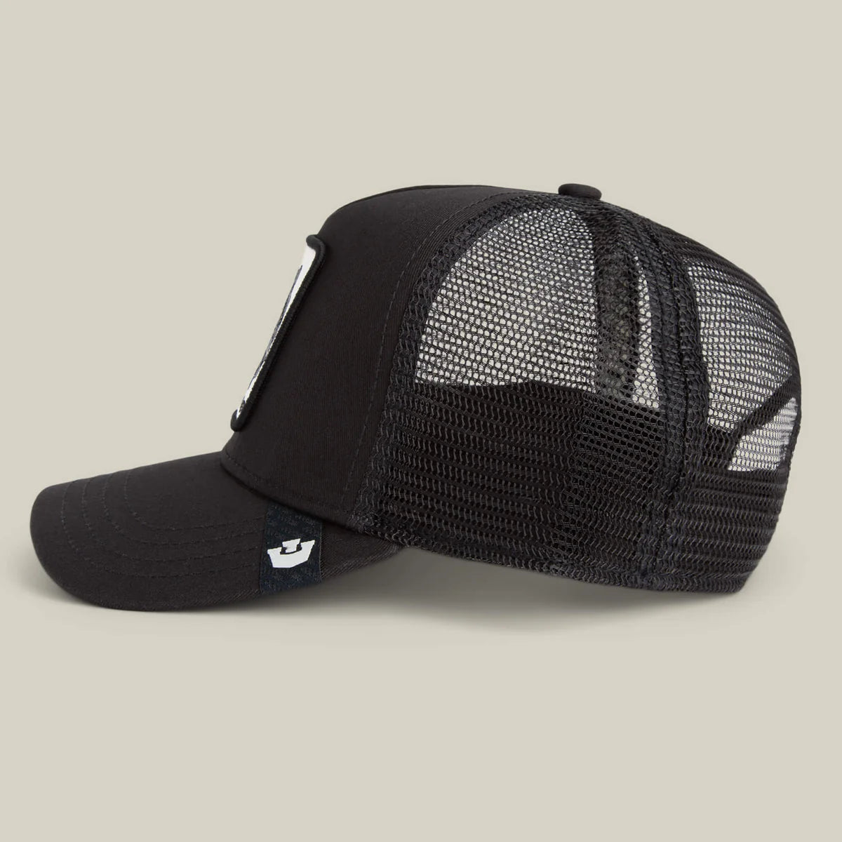 Goorin Bros lippis Panther Trucker All Black, musta, jossa verkkopaneelit taustalla, suora lippa ja pehmeä etukappale mustassa värissä ja laadukkaassa materiaalissa.