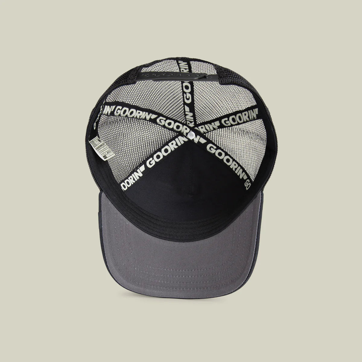Goorin Bros lippis Lion King Trucker, musta, jossa musta verkkokuppi, säädettävä takaosio ja harmaa lippa, mustavärinen logoaukkojen sisäpuolella nauhassa.