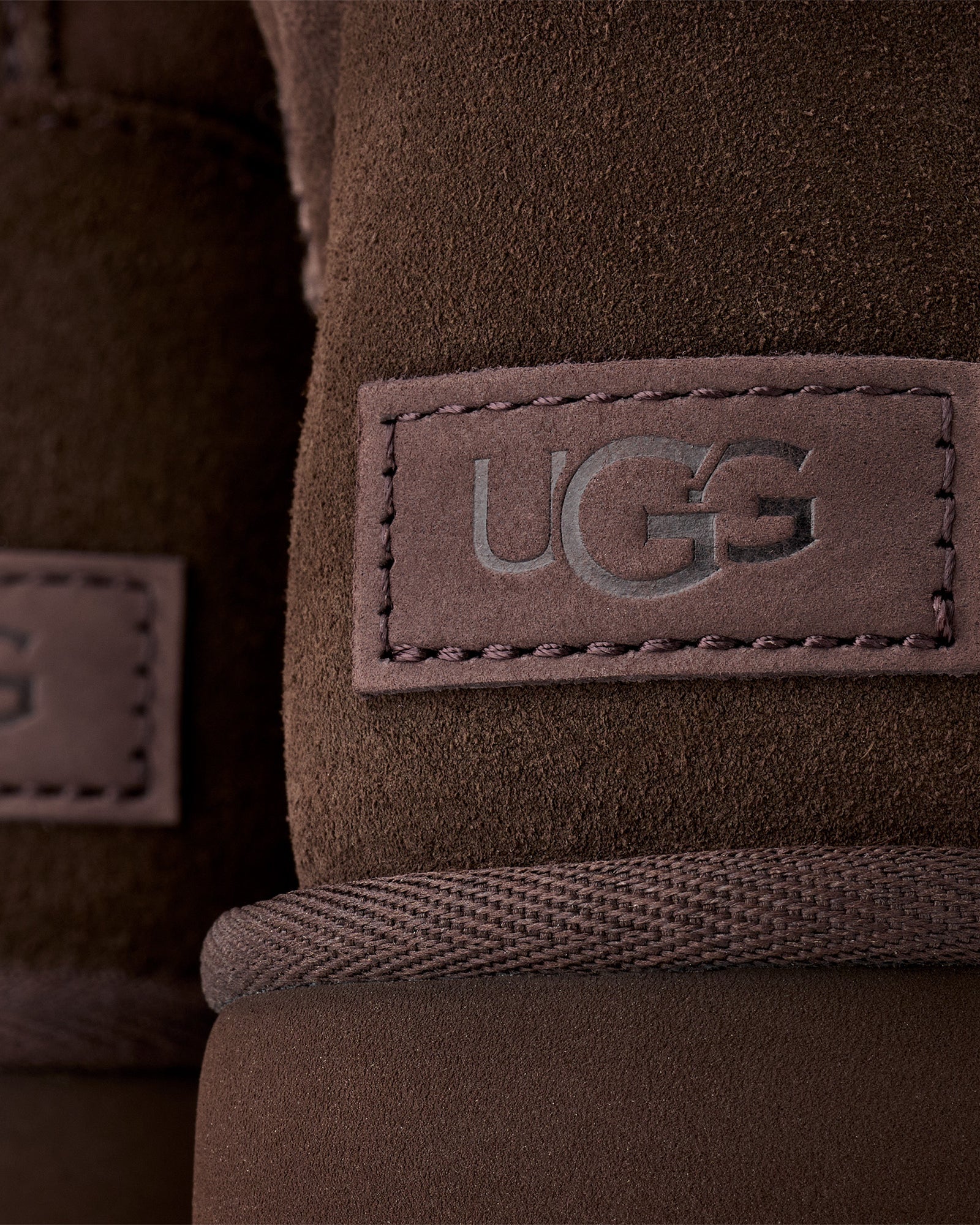 UGG naisten kengät Classic Mini II, tummanruskea, mokkanahkainen nilkkuri, jossa UGG-logomerkki, siistit ompeleet ja punottu reunus