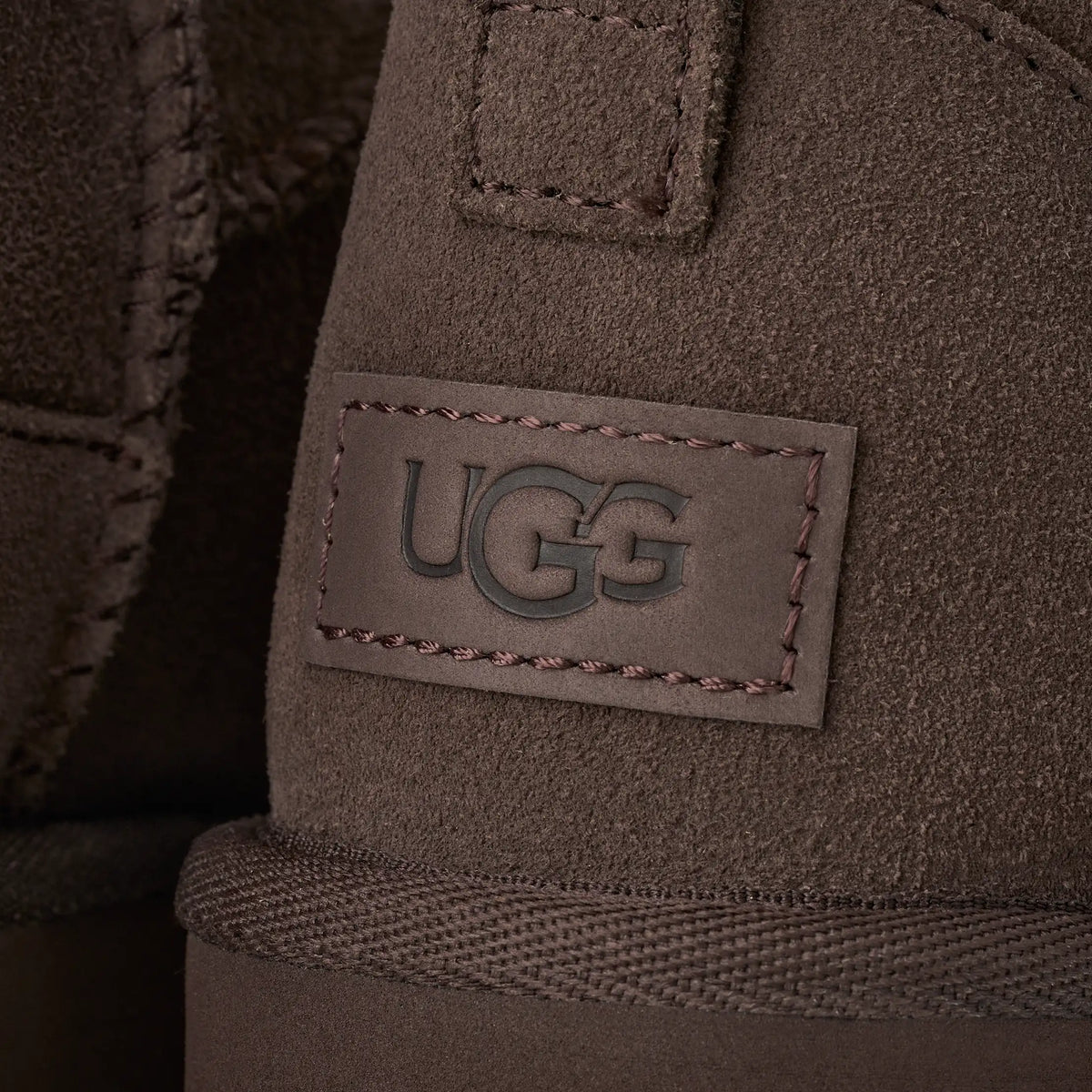 UGG naisten kengät Classic Ultra Mini, tummanruskea tummanruskealla mokkapinnalla, kohokuvioitu UGG logomerkki, vahvistetut tikkaukset ja neulottu reunus.
