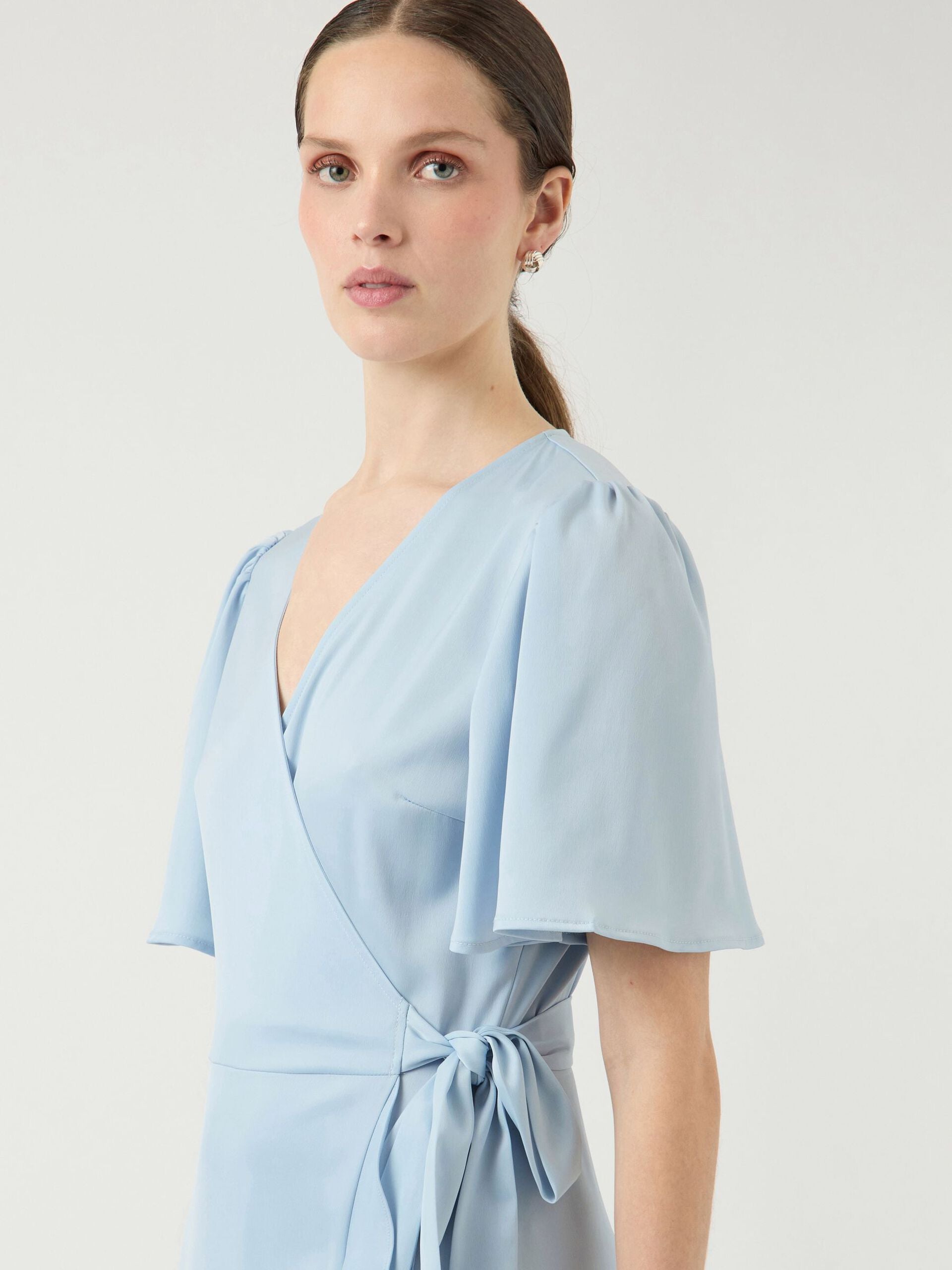 Naishahmo vaaleansinisessä Y.A.S Naisten Mekko, YASTHEA 2/4 MIDI WRAP DRESS Skyway -mekossa, jossa liehuvat hihat ja solmittava vyötärö, ajaton ja laadukas tyyli.