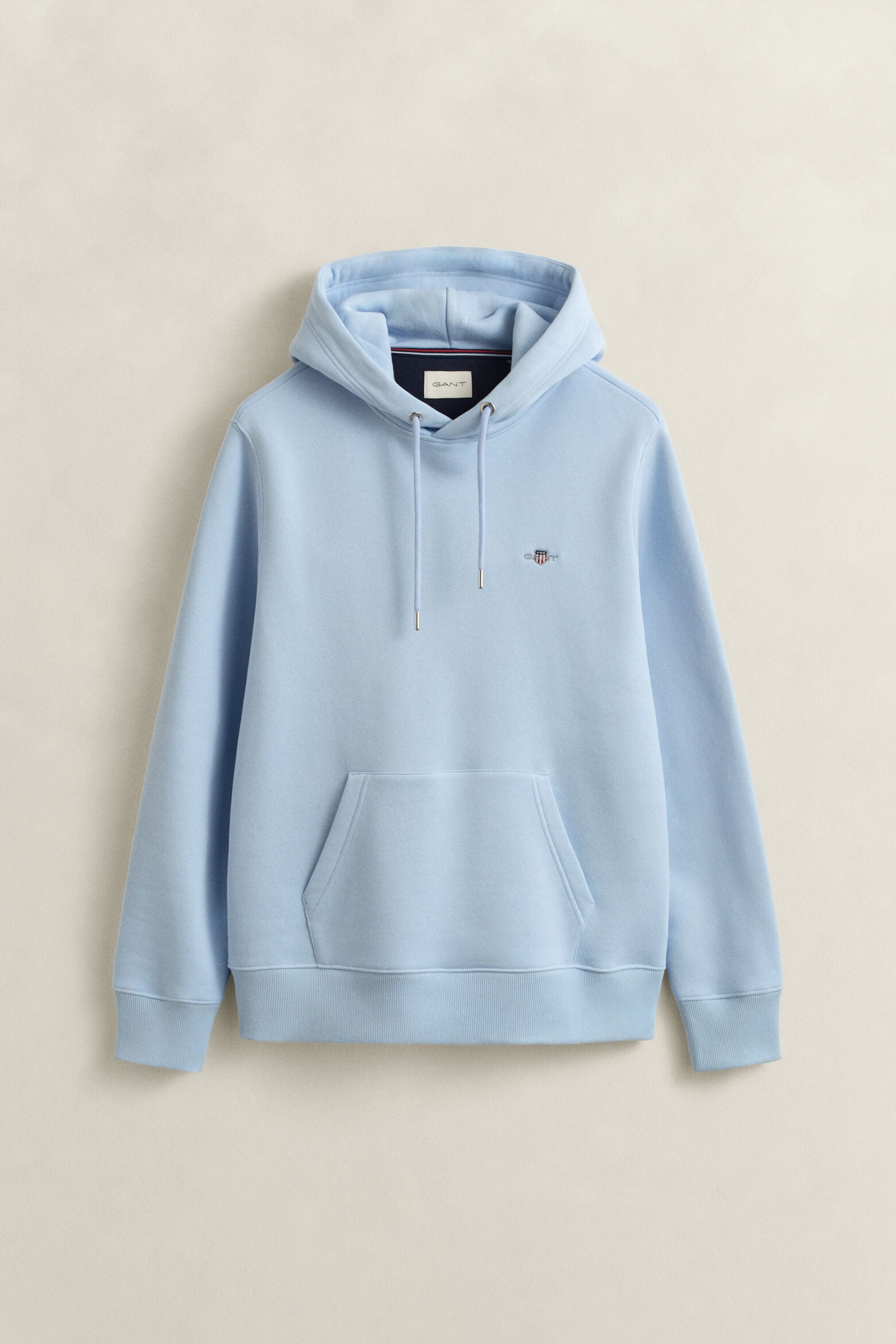 Gant miesten huppari Reg Shield Hoodie, vaaleansininen, pehmeästä materiaalista valmistettu pitkähihaisen mallinen huppari, jossa on kiristysnyörit hupussa ja etutasku.