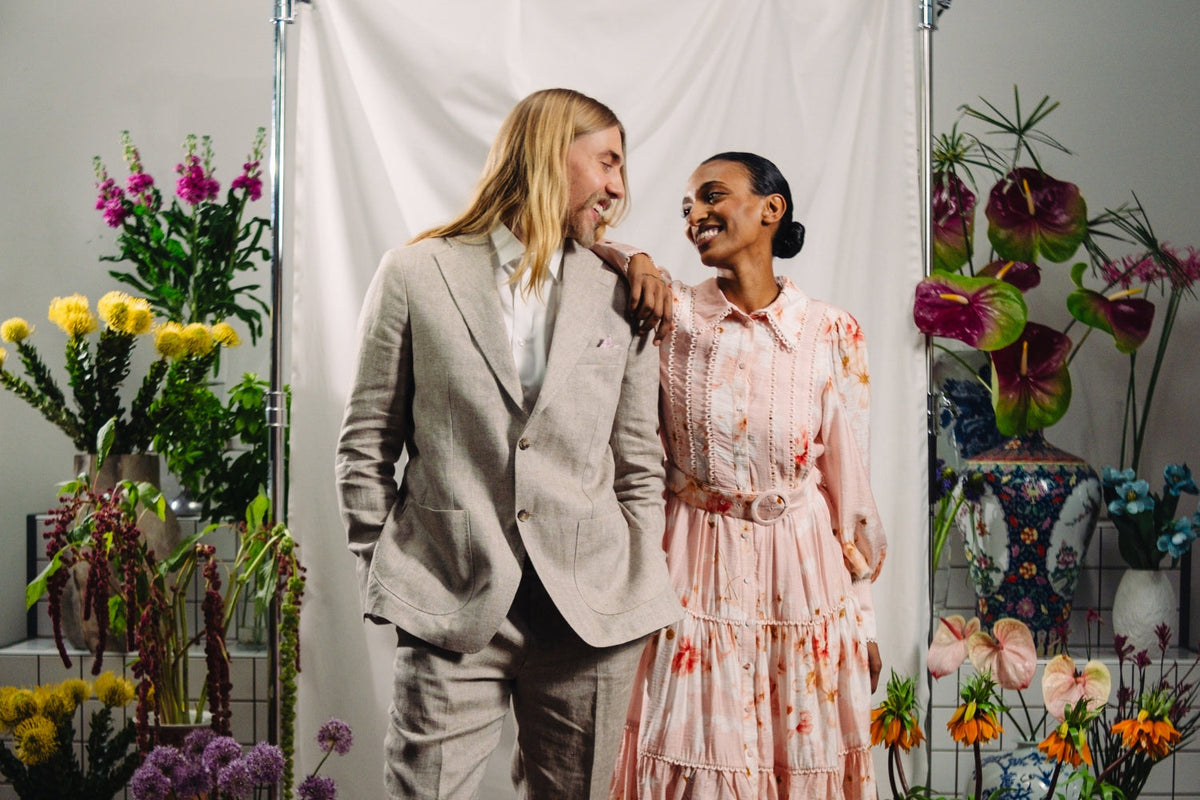 Pukuun pukeutunut mies ja mekkoon pukeutunut nainen katsovat ja nojailevat toisiinsa.