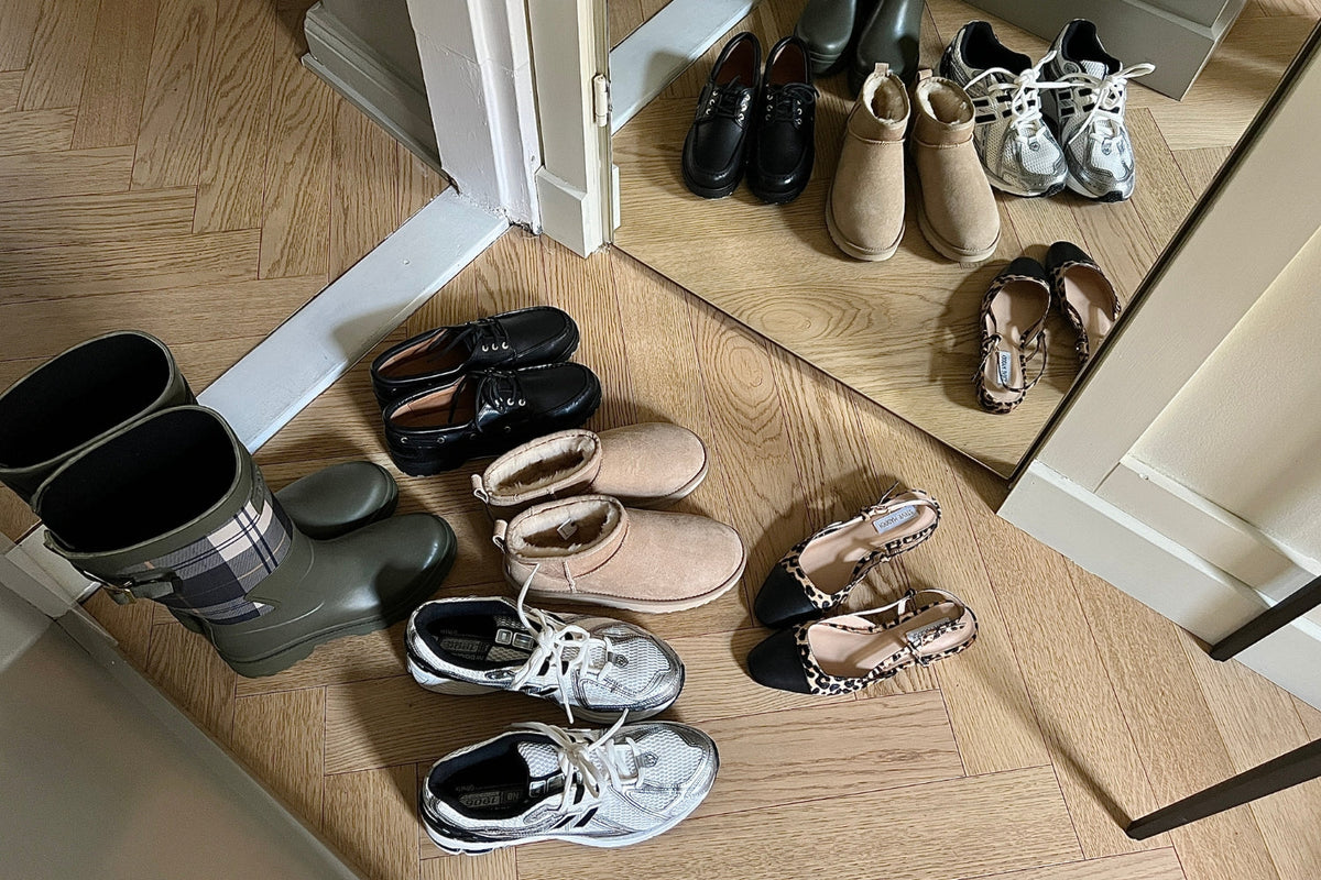 Erilaisia kenkäpareja puisella lattialla.