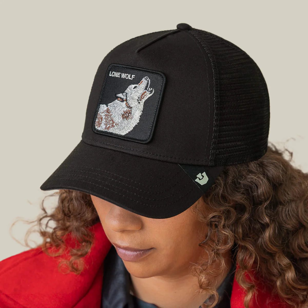 Goorin Bros lippis Lone Wolf Trucker, musta verkkopaneelilla, mustaa tiivistä kangasta, edessä kirjailtu susiaiheinen merkki ja hieman kaartuva lippa.