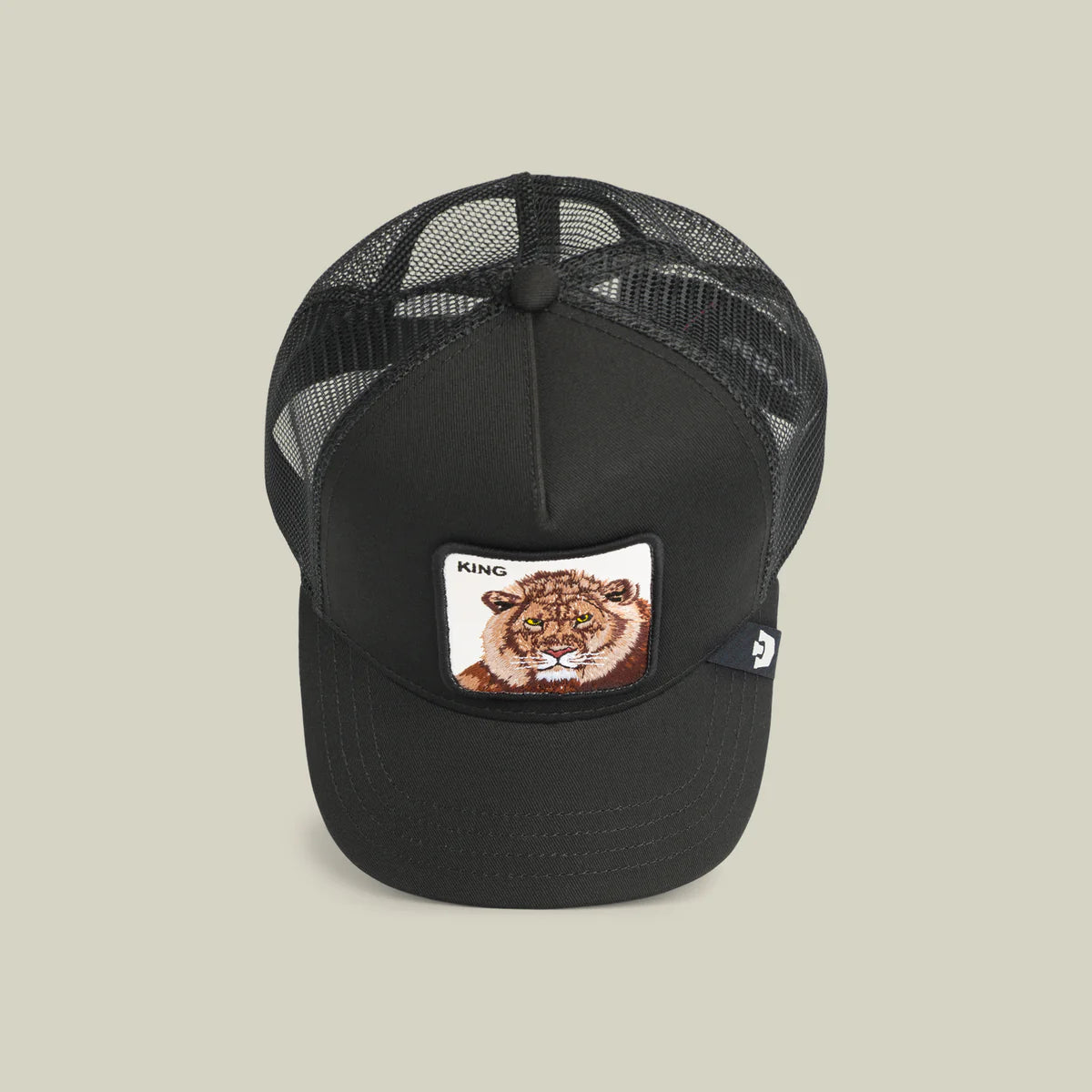 Goorin Bros lippis Lion King Trucker, musta, jossa musta verkkomateriaali takana ja edessä lion-kuviointi, säädettävä takapanta ja kaareva lippa.