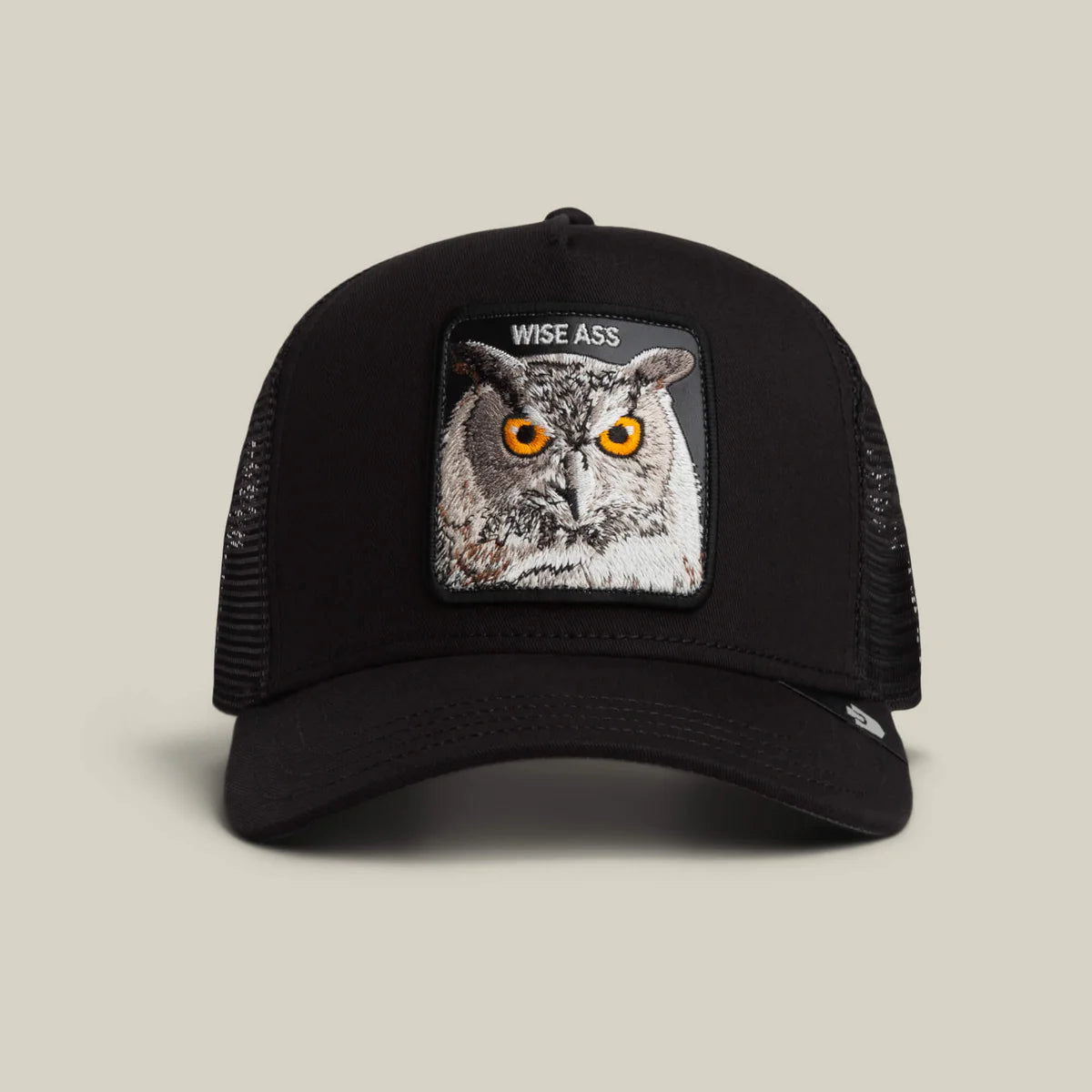 Goorin Bros lippis Wise Ass Owl Trucker, musta, jossa musta etupaneeli ja verkkomainen takaosa, suorakaiteen muotoinen pöllökuvio ja suora lippalakki.
