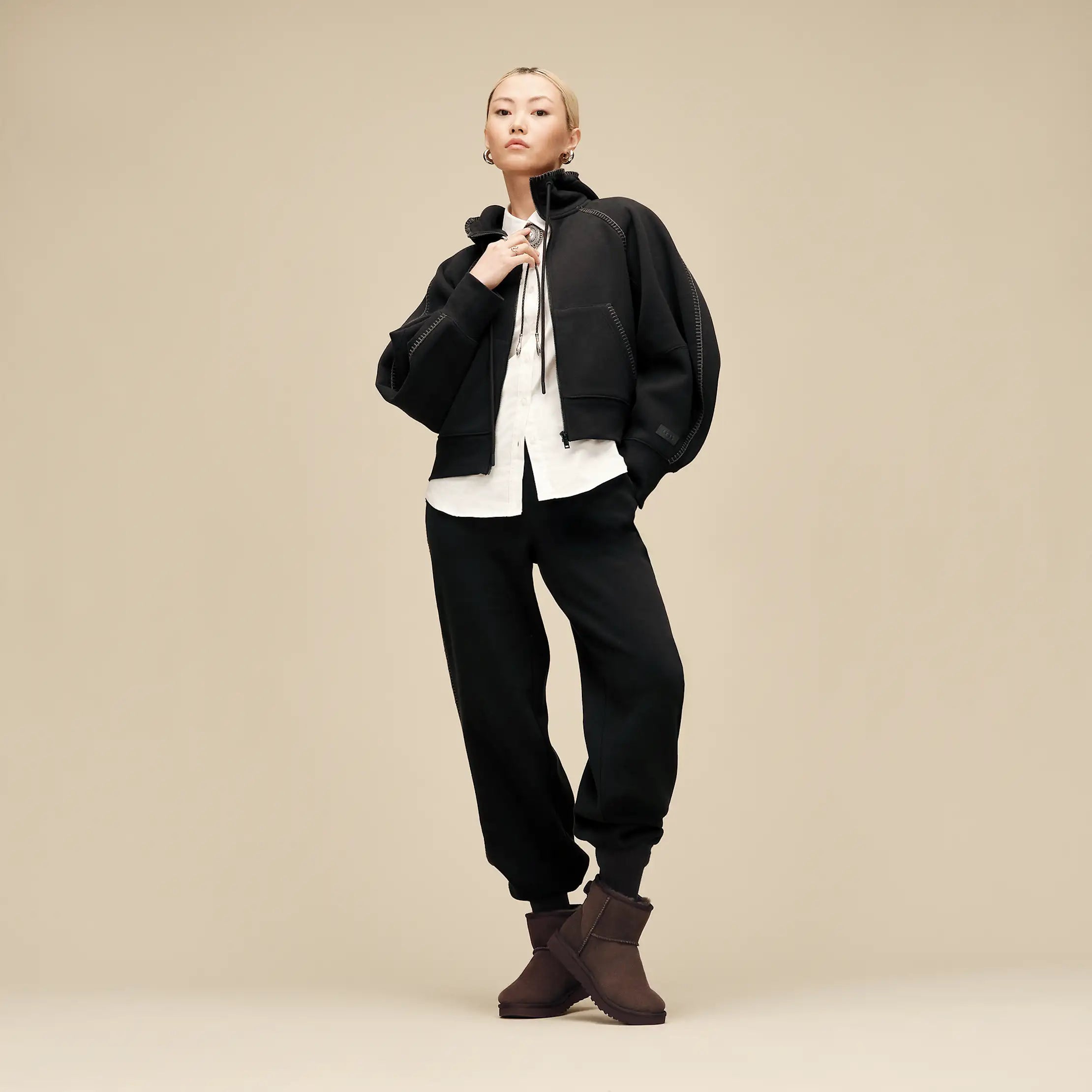 UGG naisten kengät Classic Mini II, tummanruskea, lyhytvartiset tummanruskeat nilkkurit, joissa on pehmeän mokkanahkainen pinta ja pyöristetty kärki.