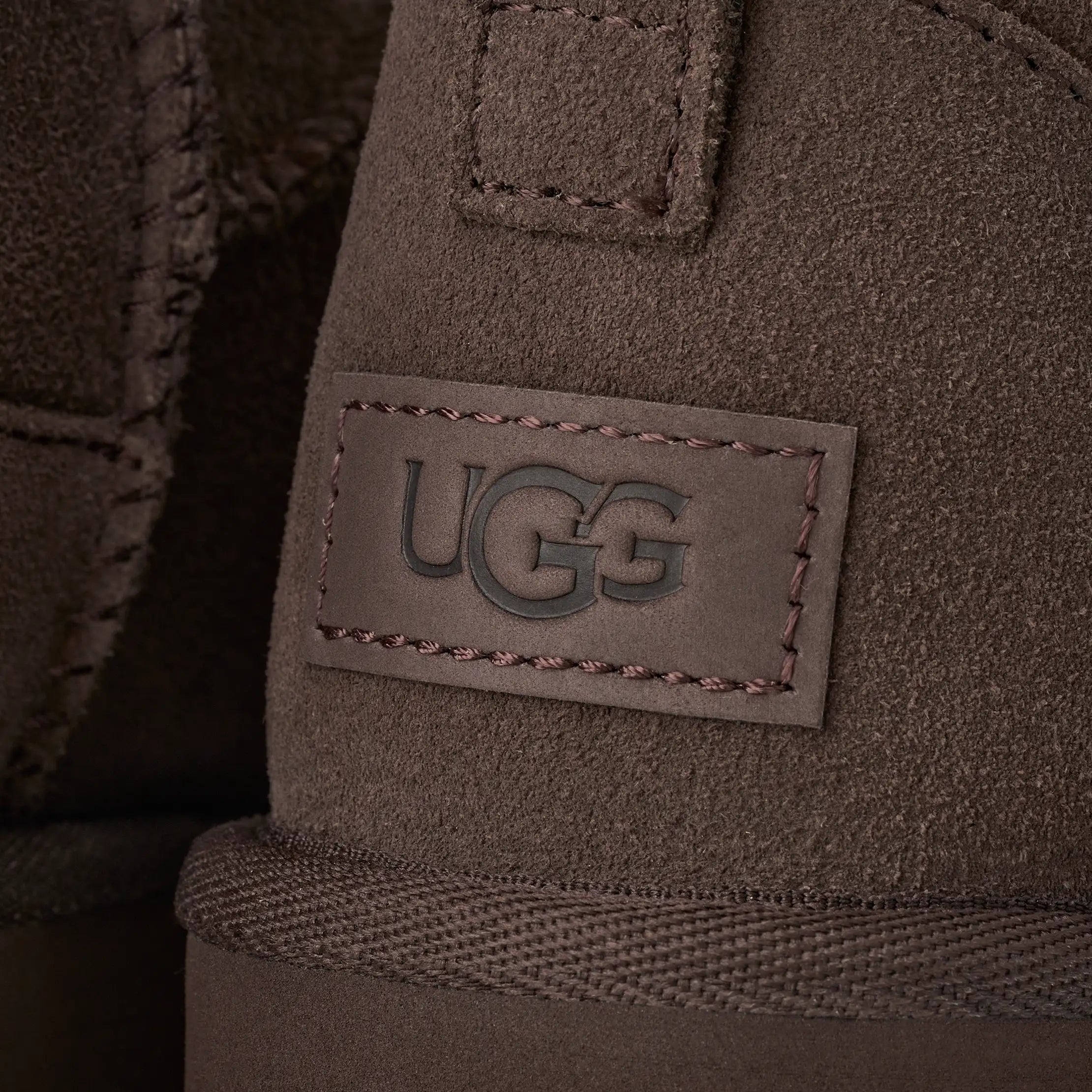 UGG naisten kengät Classic Ultra Mini, tummanruskea tummanruskealla mokkapinnalla, kohokuvioitu UGG logomerkki, vahvistetut tikkaukset ja neulottu reunus.