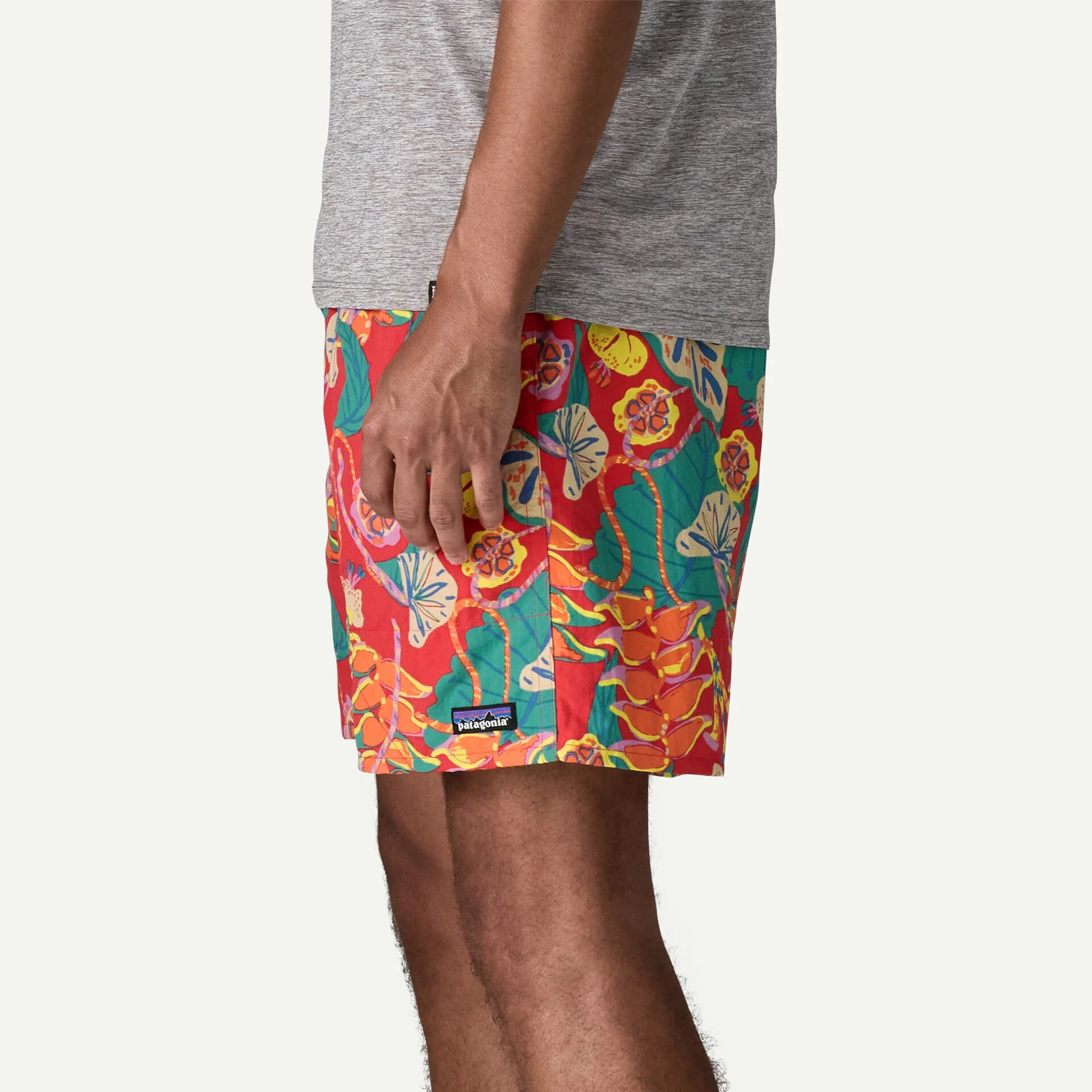Patagonia miesten shortsit M's Baggies Longs - 7 in., monivärinen kuosi, jossa kirkkaanpunainen pohja ja värikäs, trooppinen kasvi- ja hedelmäkuviointi.