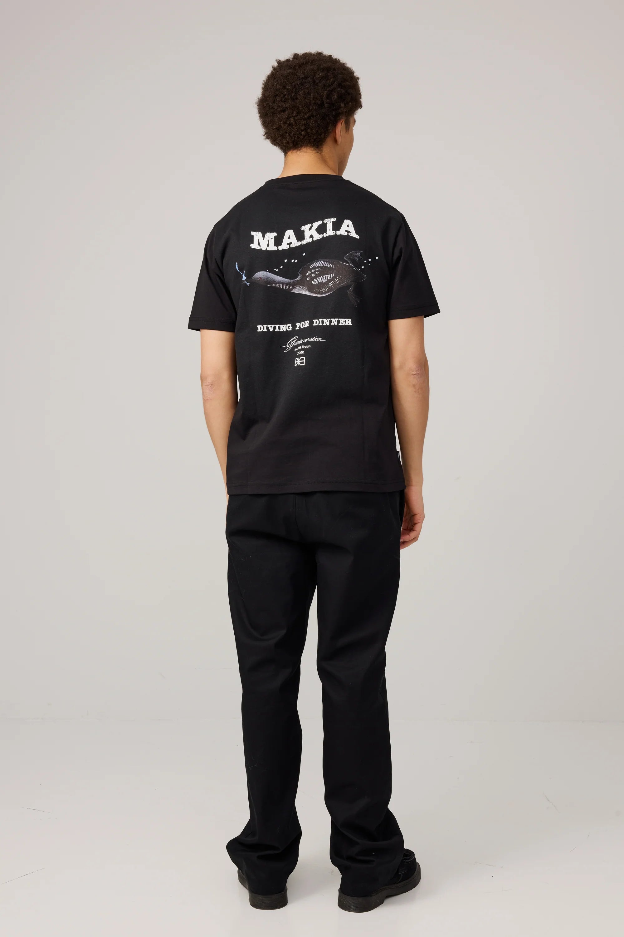 Makia miesten t-paita Erik T-shirt, musta, jossa on lyhythihainen klassinen leikkaus ja takana valkoinen painatus meriaiheisella kuvituksella.