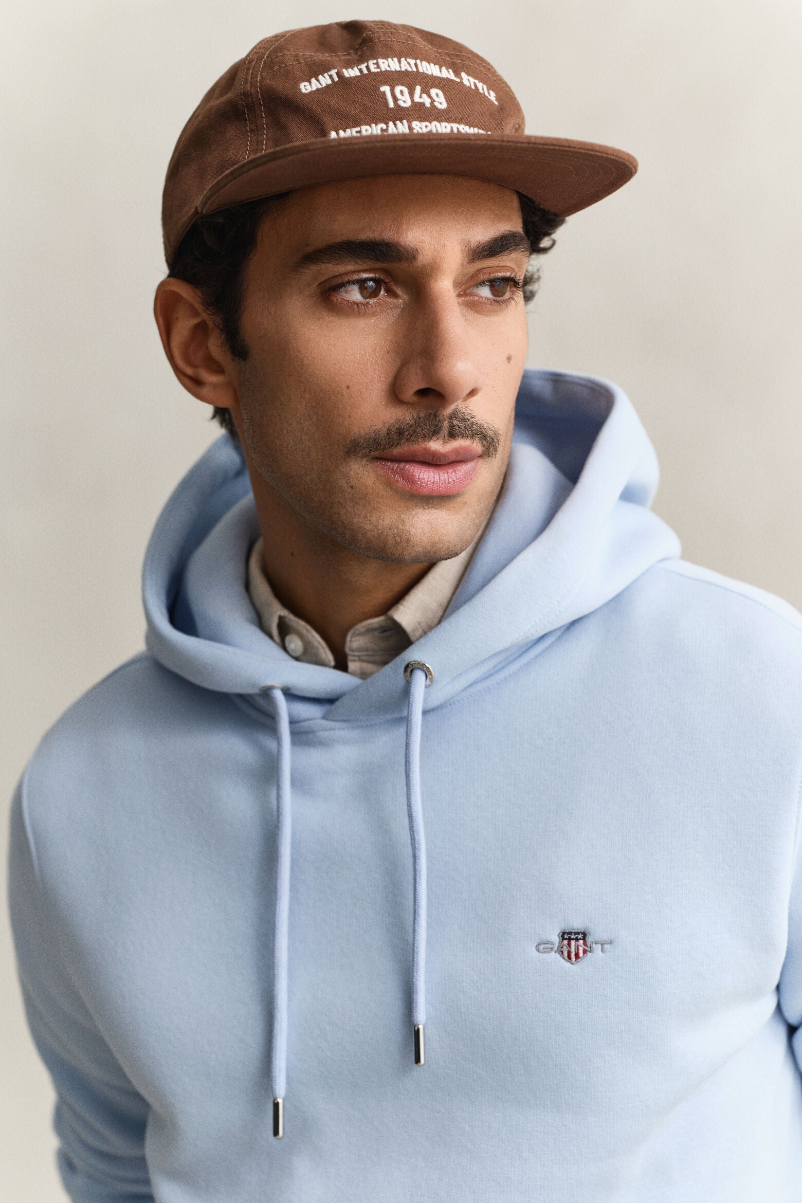Gant miesten huppari Reg Shield Hoodie, vaaleansininen, pehmeästä kankaasta valmistettu kevyt huppari, jossa on säädettävä nyörillinen huppu ja pienikokoinen logopainatus rinnassa.