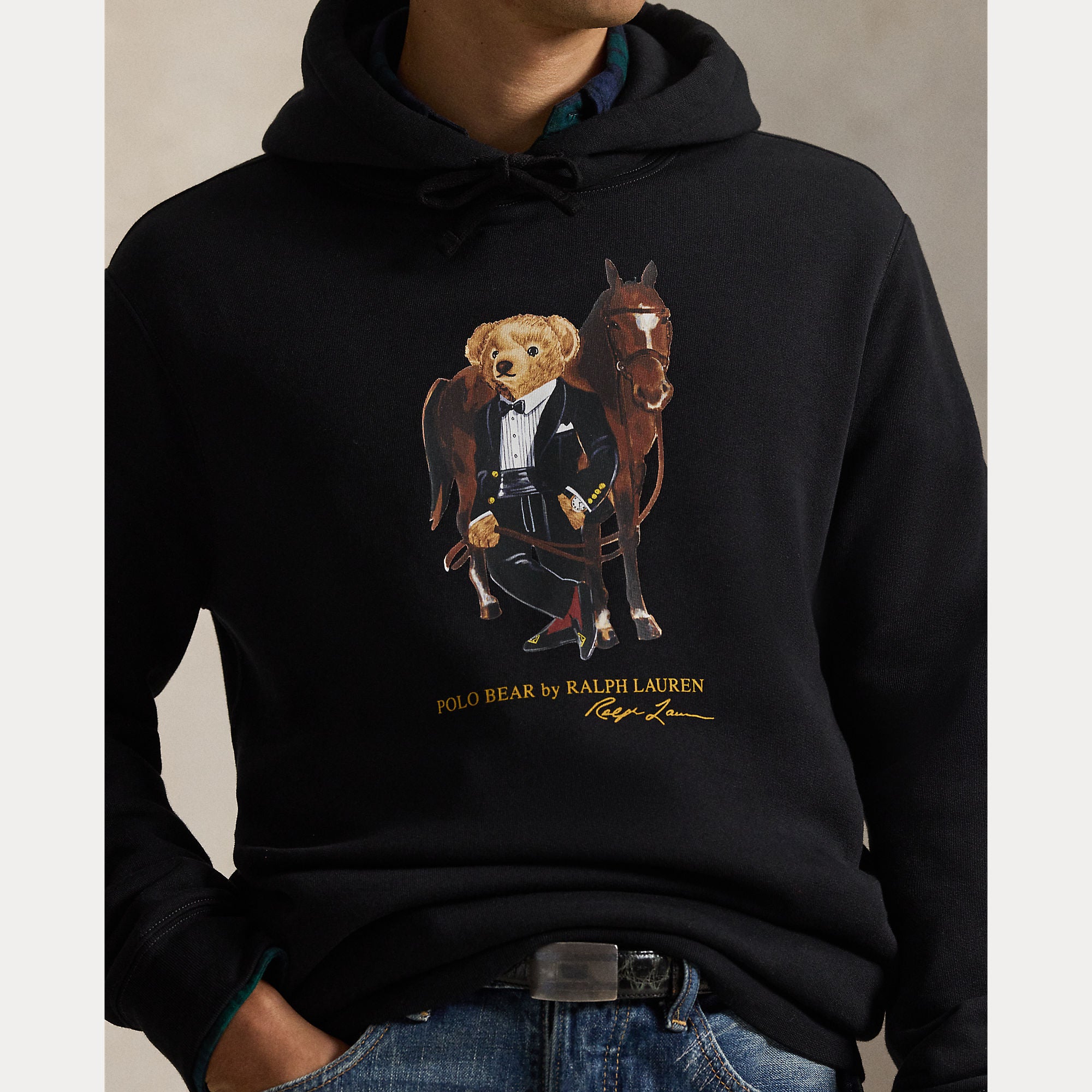 Polo Ralph Lauren miesten huppari Polo Bear Fleece Hoodie, musta, on musta fleece-materiaalia oleva huppari, jossa on nauhakiinnitteinen huppu ja etuosassa painokuva nukeutuneesta karhuhahmosta hevosen kanssa.